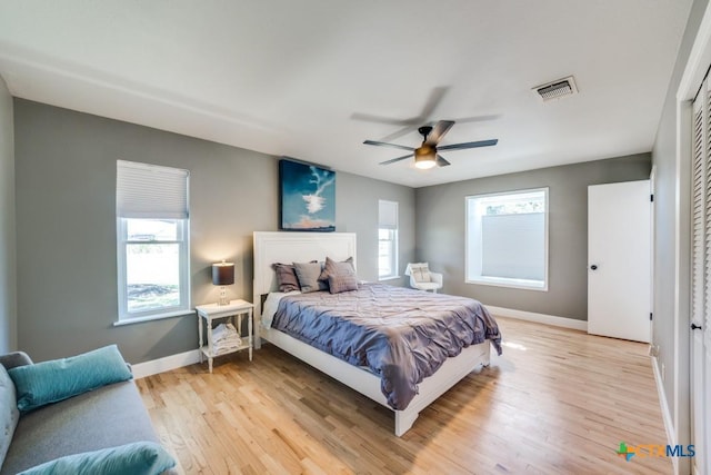 bedroom featuring multiple windows, baseboards, visible vents, and light wood finished floors