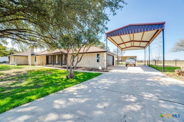 view of front facade featuring stone siding, a front lawn, a detached carport, and driveway