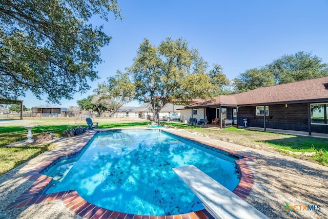 outdoor pool featuring a lawn and a diving board