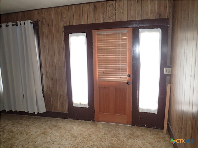 carpeted foyer entrance with wood walls