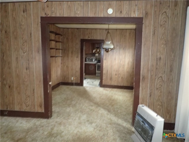 unfurnished dining area featuring light colored carpet, wooden walls, and heating unit