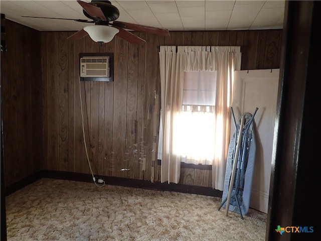 carpeted spare room featuring an AC wall unit, ceiling fan, and wood walls