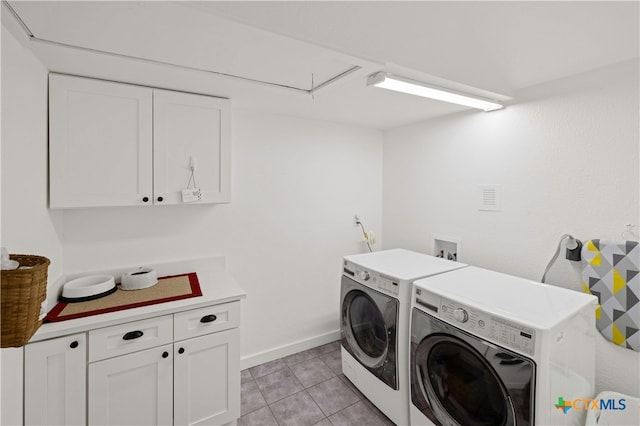 clothes washing area with light tile patterned flooring, cabinets, and washing machine and clothes dryer