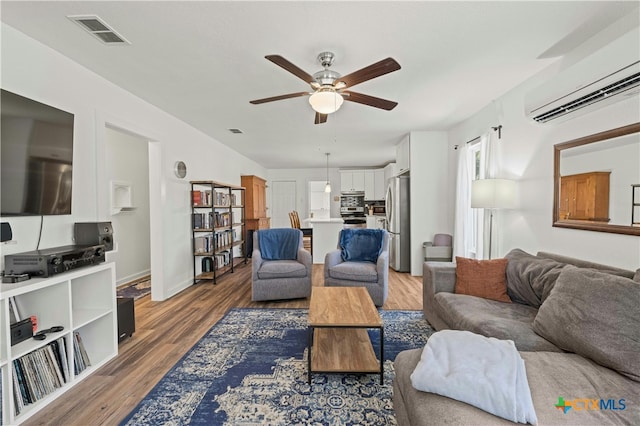 living room featuring ceiling fan, wood-type flooring, and a wall mounted air conditioner