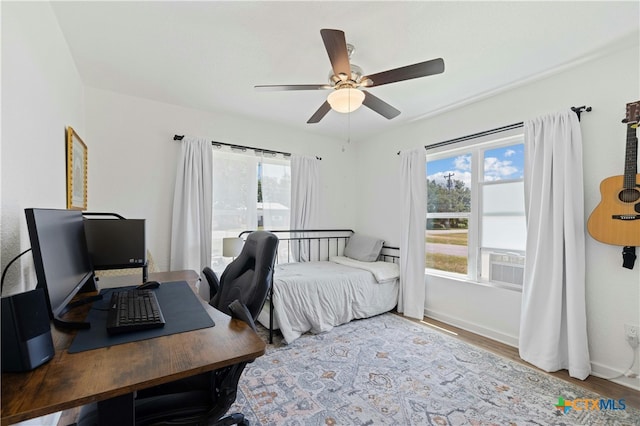 bedroom featuring ceiling fan, multiple windows, and wood-type flooring