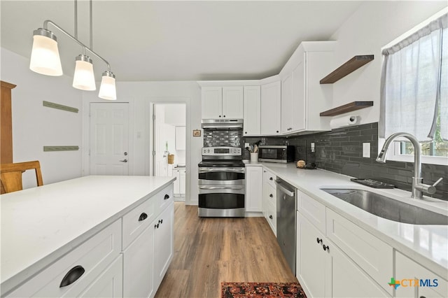 kitchen featuring stainless steel appliances, white cabinets, hanging light fixtures, sink, and dark hardwood / wood-style floors