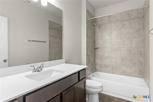 full bathroom with vanity, tiled shower / bath combo, hardwood / wood-style flooring, and toilet