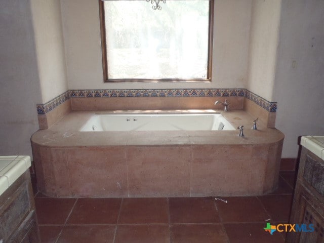 bathroom featuring a relaxing tiled tub and tile patterned flooring