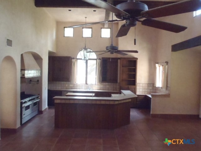 kitchen featuring a kitchen island, white range with gas stovetop, a high ceiling, and beam ceiling