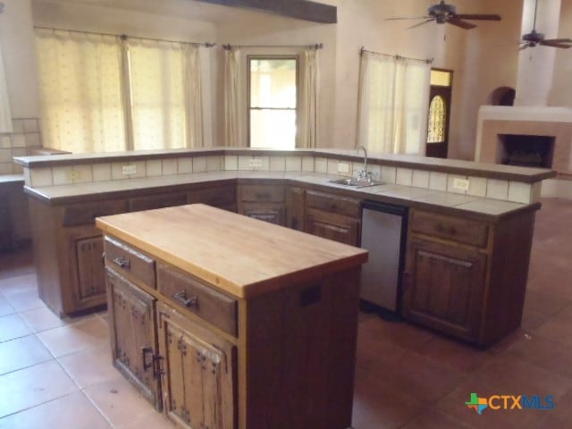 kitchen featuring kitchen peninsula, sink, a center island, and light tile patterned flooring