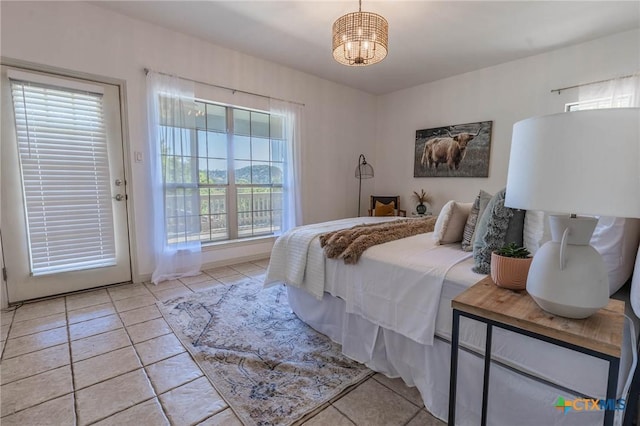 bedroom featuring access to outside, light tile patterned floors, and an inviting chandelier