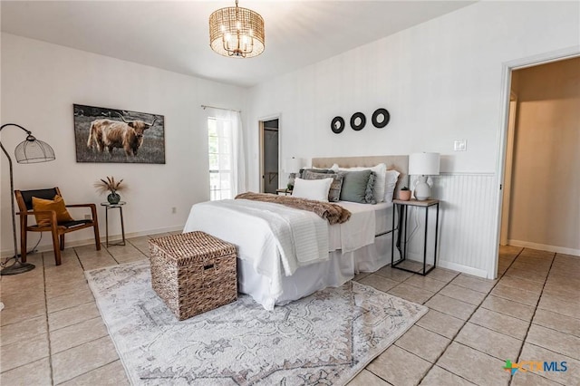 bedroom with light tile patterned floors and an inviting chandelier