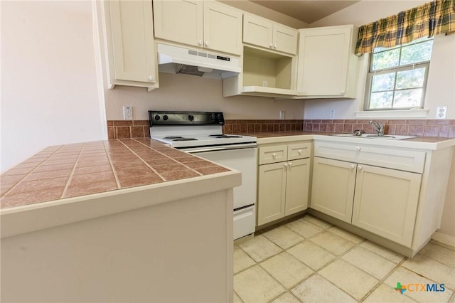 kitchen featuring a sink, a peninsula, electric stove, under cabinet range hood, and tile countertops
