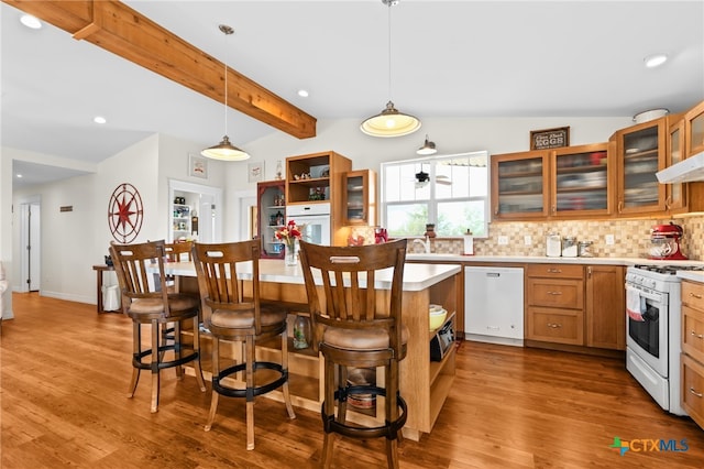 kitchen with white appliances, vaulted ceiling with beams, a breakfast bar, and light hardwood / wood-style floors