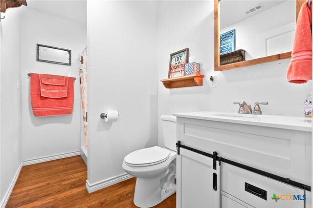 bathroom featuring toilet, vanity, hardwood / wood-style flooring, and curtained shower