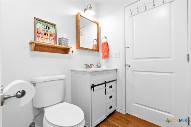 bathroom with hardwood / wood-style floors, vanity, and toilet