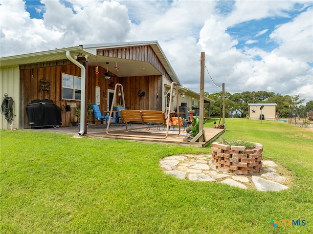 back of property featuring a patio area, a yard, and an outdoor fire pit