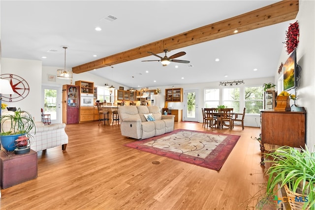 living room with light wood-type flooring, vaulted ceiling with beams, a healthy amount of sunlight, and ceiling fan