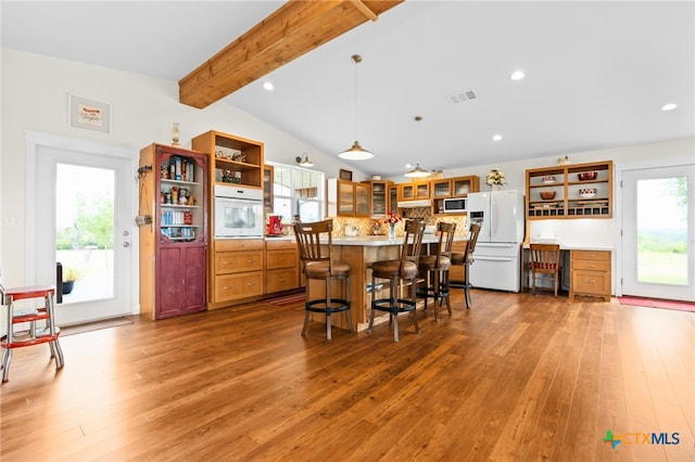 kitchen with wood-type flooring, vaulted ceiling with beams, a center island, pendant lighting, and white appliances