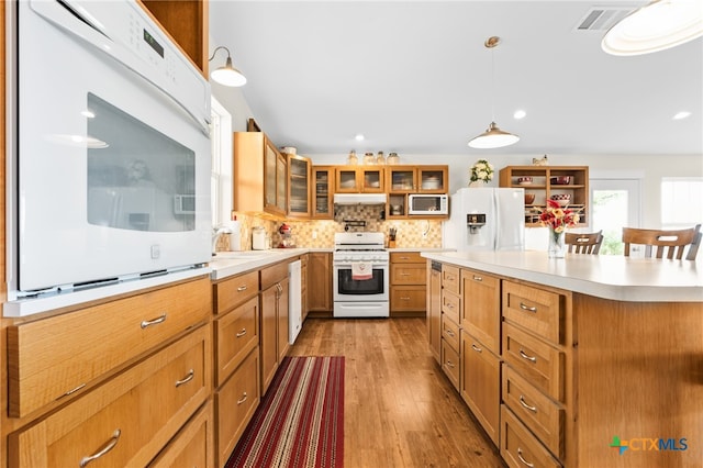 kitchen with a kitchen island, light wood-type flooring, decorative light fixtures, sink, and white appliances