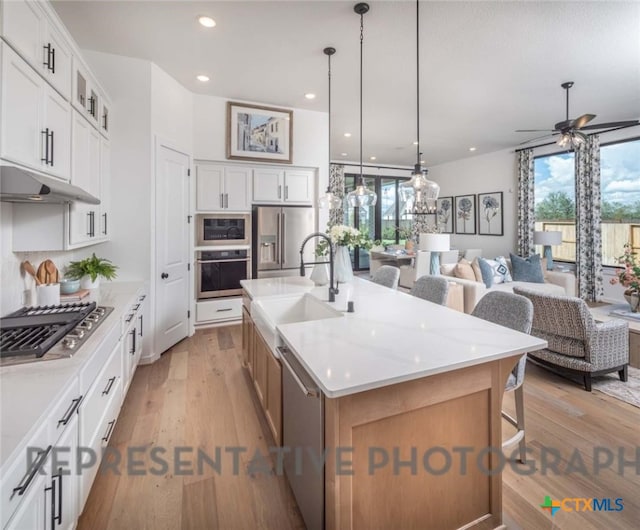 kitchen with a large island with sink, sink, white cabinets, and stainless steel appliances