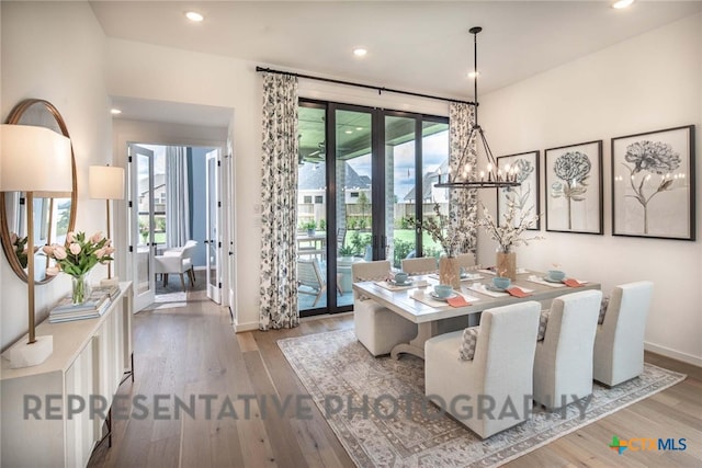 dining room with french doors, a notable chandelier, and light wood-type flooring