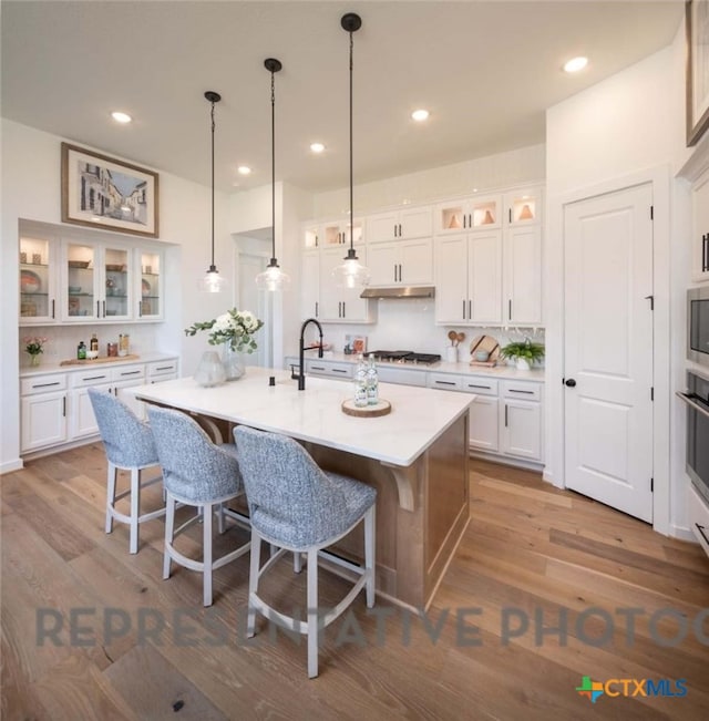 kitchen with an island with sink, white cabinets, light hardwood / wood-style floors, and gas cooktop