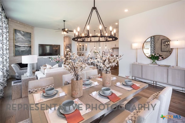 dining area featuring hardwood / wood-style flooring, ceiling fan with notable chandelier, and sink