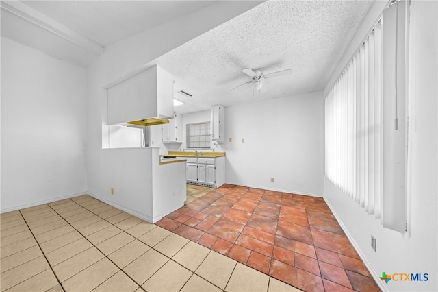 2310 Bunker Hill Dr, Temple, TX 76504 - kitchen with healthy amount of natural light, a ceiling fan, white cabinets, light tile patterned flooring, and a textured ceiling