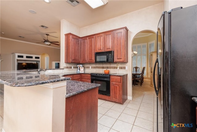 kitchen featuring arched walkways, visible vents, dark stone countertops, a peninsula, and black appliances