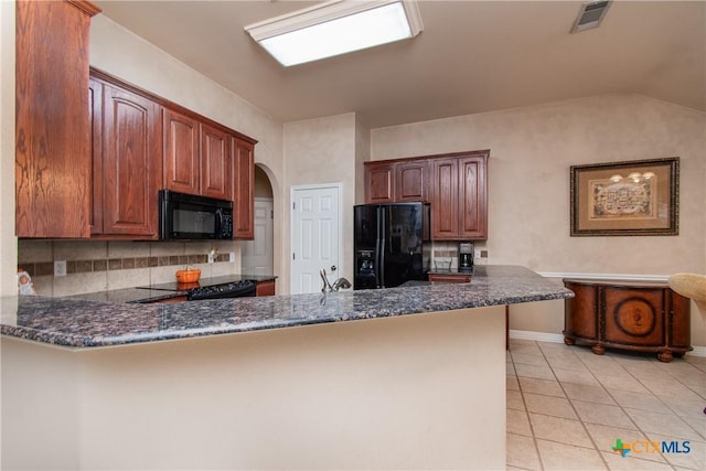 kitchen featuring dark stone counters, black appliances, a peninsula, and visible vents