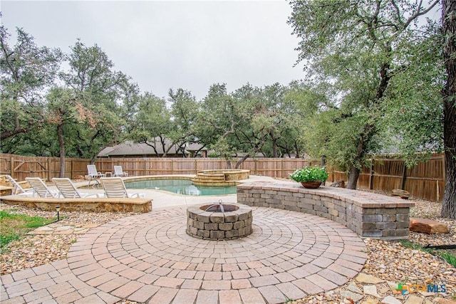 view of patio / terrace with a pool with connected hot tub, a fenced backyard, and a fire pit