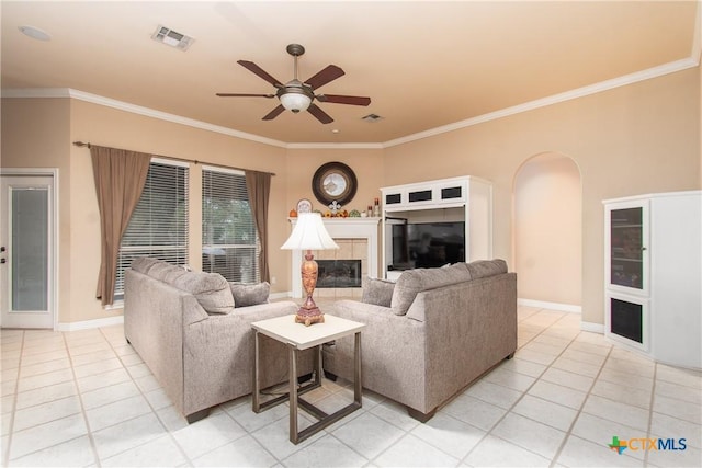 living area with light tile patterned floors, arched walkways, visible vents, ornamental molding, and a tiled fireplace