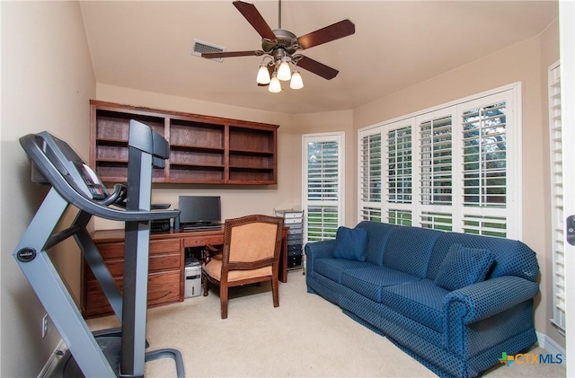 office area featuring light carpet, built in study area, visible vents, and a ceiling fan