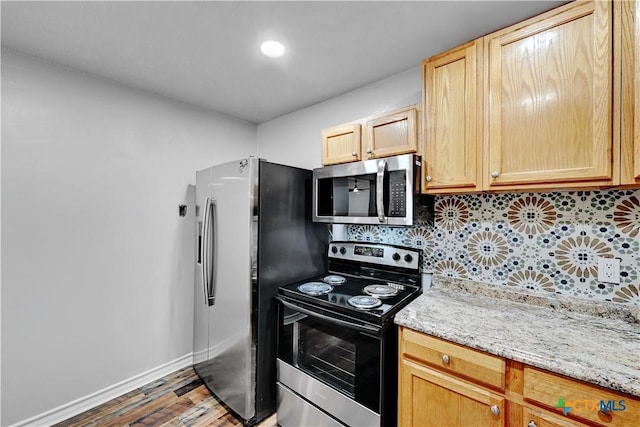 kitchen with light brown cabinets, wood finished floors, baseboards, appliances with stainless steel finishes, and decorative backsplash