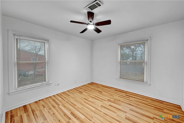 unfurnished room featuring a ceiling fan, visible vents, baseboards, and wood finished floors