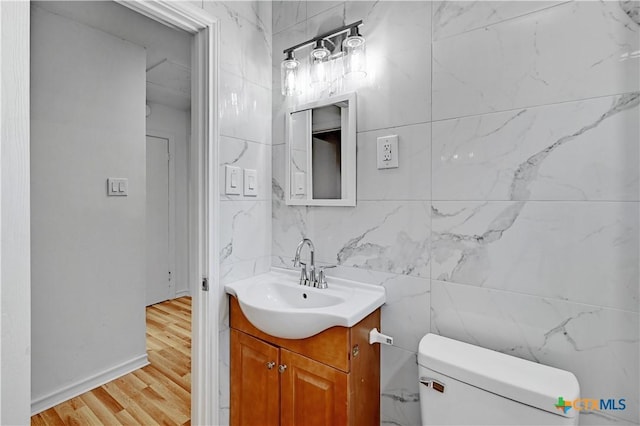 half bathroom featuring toilet, wood finished floors, and vanity