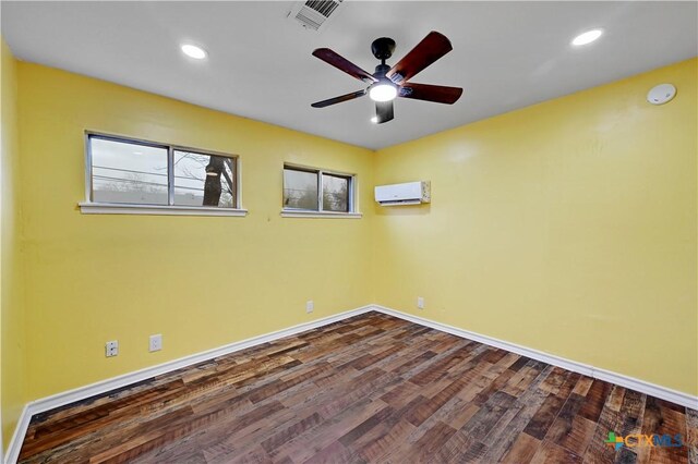 empty room with dark wood-type flooring, an AC wall unit, visible vents, and baseboards