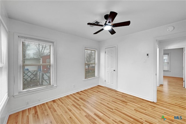 empty room with ceiling fan, light wood-type flooring, and baseboards