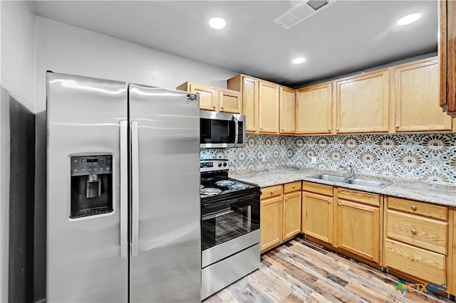 kitchen with stainless steel appliances, visible vents, a sink, and light brown cabinets