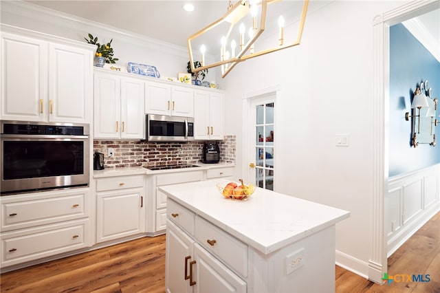 kitchen with light wood-type flooring, white cabinetry, ornamental molding, and stainless steel appliances