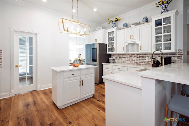 kitchen with light hardwood / wood-style flooring, a kitchen bar, stainless steel refrigerator, and white cabinets