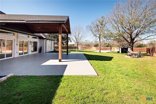 view of yard with a shed, ceiling fan, and a patio area