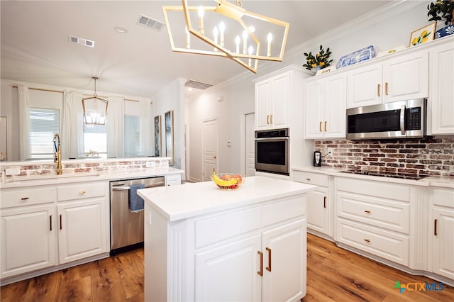 kitchen with stainless steel appliances, light hardwood / wood-style floors, hanging light fixtures, tasteful backsplash, and white cabinetry