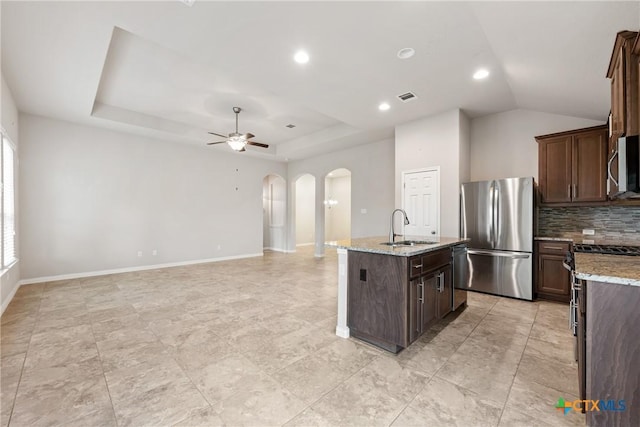 8113 Cannon Ct, Lago Vista, TX 78645 - kitchen featuring appliances with stainless steel finishes, arched walkways, ceiling fan, a kitchen island with sink, and decorative backsplash