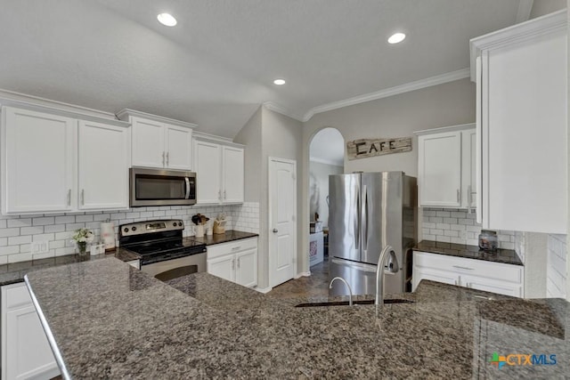 kitchen featuring appliances with stainless steel finishes, dark stone counters, decorative backsplash, and white cabinets