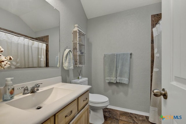 bathroom featuring lofted ceiling, toilet, and vanity