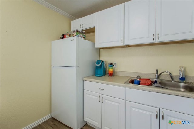 kitchen featuring dark hardwood / wood-style flooring, ornamental molding, sink, white cabinets, and white fridge