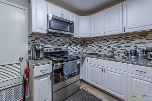 kitchen featuring decorative backsplash, white cabinetry, sink, and appliances with stainless steel finishes