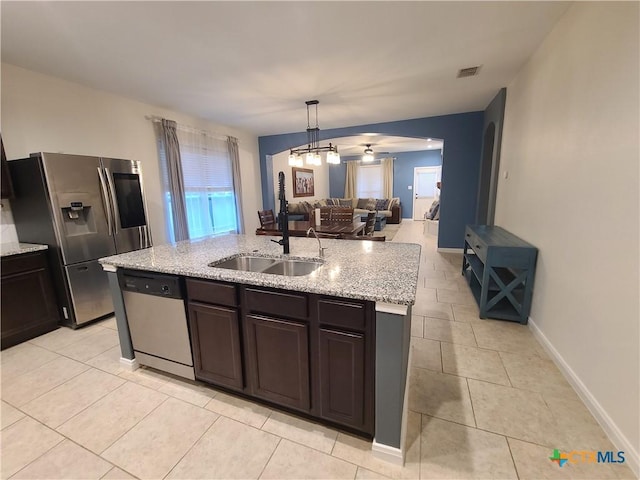 kitchen with pendant lighting, light stone countertops, stainless steel appliances, and a kitchen island with sink